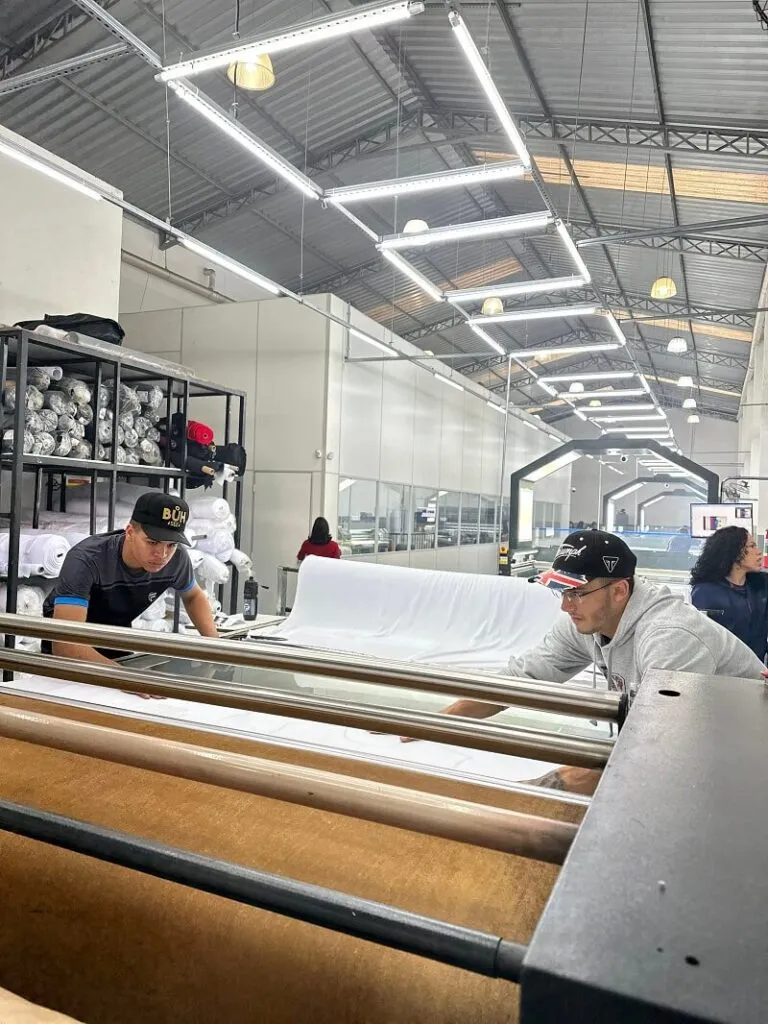 Colaboradores operando a máquina de estampar tecidos na fábrica