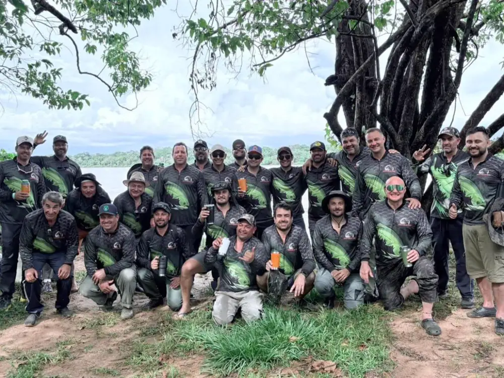 Grupo de amigos em pescaria na beira do rio com camisetas pretas e verdes