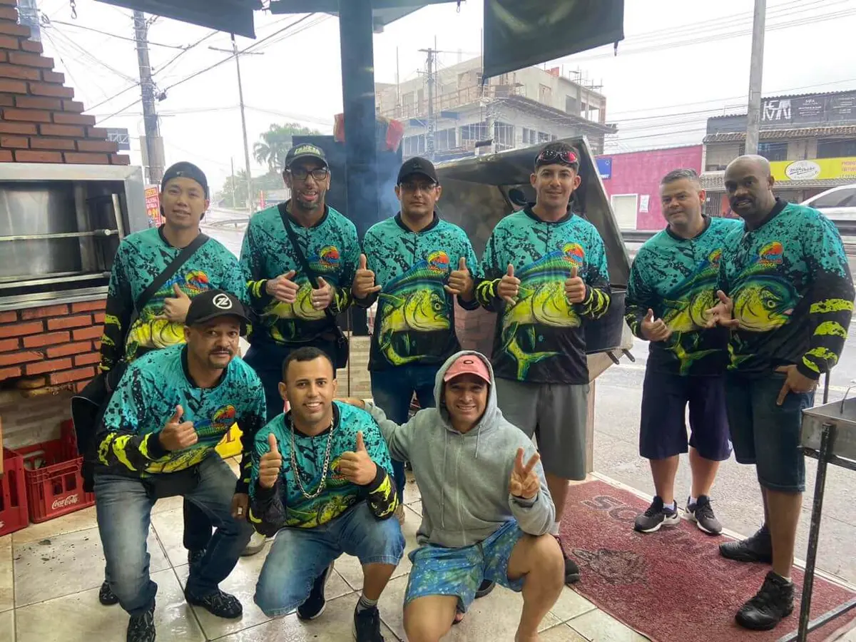 Amigos fazendo sinal de positivo vestindo camisetas de pesca verdes com dourado estampado